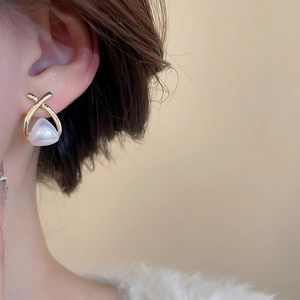 Detail view of elegant gold-tone flower pearl earrings worn by a model in soft light