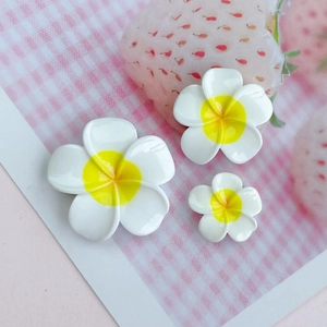 Detailed comparison of three different sizes of glossy white resin plumeria flower charms
