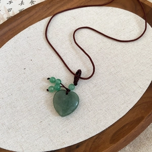 Detail of heart-shaped natural stone pendant on woven cord with vintage aesthetic