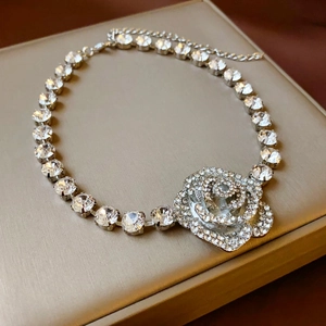 Macro detail of silver-toned necklace featuring a sparkling crystal-studded rose pendant
