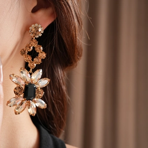 Gros plan sur la boucle d'oreille fleur vintage dorée avec cristaux et pierre noire