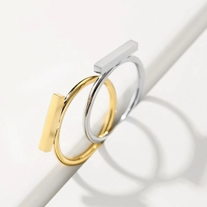 Macro shot of gold and silver minimalist stainless steel bar rings on a white pedestal
