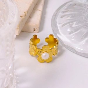 Golden flower-shaped open ring with white pearl on a minimal decorative background