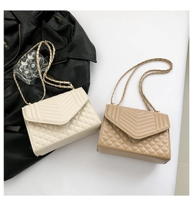 Close-up of quilted crossbody bags in beige and khaki with gold chain and metal lock