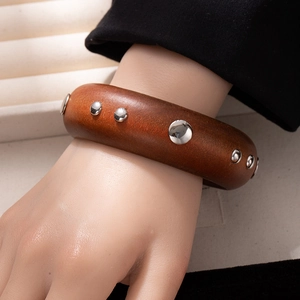 Retro wide wood bangle with silver metal rivets worn on wrist for a vintage fashion look