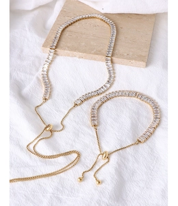 Dettaglio del set collana e bracciale dorato regolabile con zirconi quadrati