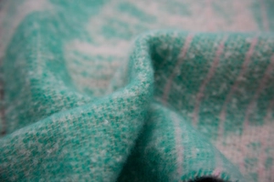 Detail of teal and white jacquard knit scarf showing soft textured ginkgo leaf fabric