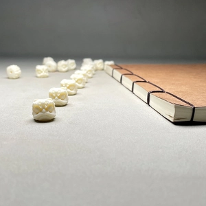 Macro shot of ivory fruit lion head beads for DIY jewelry with a vintage book background