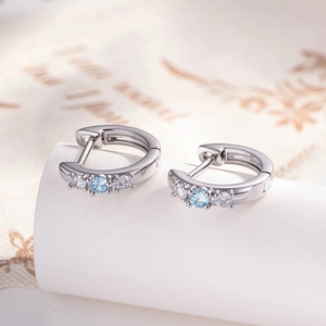 Silver copper earrings featuring round blue and white zircon stones on a white stand