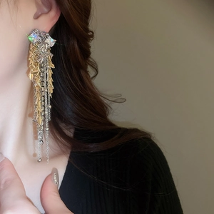 Macro shot of gold and silver tassel earrings with crystals on an ear model