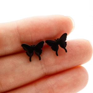 Minimalist black butterfly stainless steel stud earrings for women shown on hand