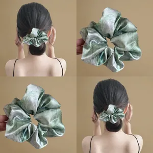 Detail of starry blue satin scrunchie with elegant marble tie-dye texture and silk finish