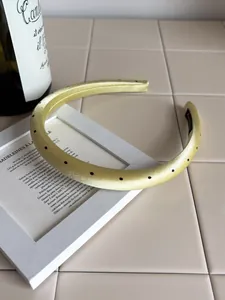 Detailed macro view of yellow satin headband with black polka dots and non-slip lining