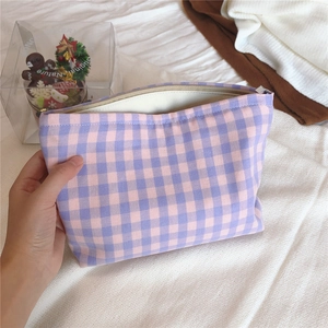 Detail of hand holding a purple plaid cotton makeup bag with high quality fabric texture