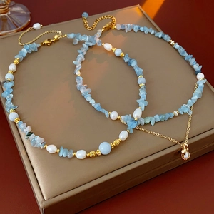 Detail view of freshwater pearl and aquamarine beaded necklaces with gold accents