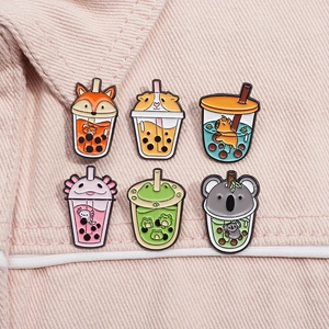 Close-up of six cute animal bubble tea enamel pins on pink denim fabric background