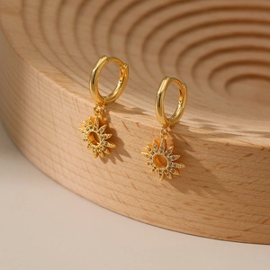 Detail of 18K gold-plated sunburst hoop earrings featuring white zircon pavé on wood stand