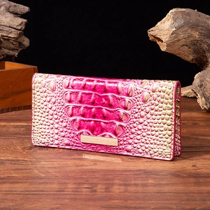 Detailed close-up of rose red crocodile embossed leather wallet with metal buckle closure
