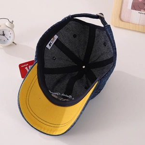 Detail view of denim baseball cap with yellow brim underside and Beach Style embroidery