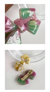 Detail of the golden France Handmade text on acetate bow clips with metal hair clamps