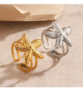Detail of gold and silver starfish open rings with textured finish on natural stone