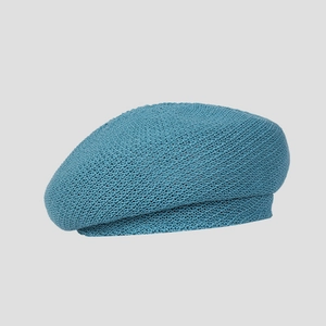 Detailed texture of blue knitted beret with honeycomb weave pattern on grey background