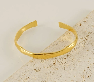 Detailed macro view of 18K gold plated bamboo-style cuff bracelet on stone base