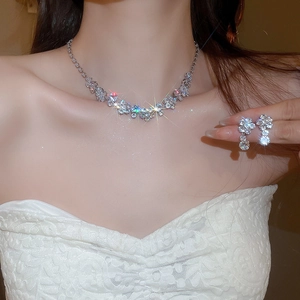 Close-up of silver necklace and earrings set with sparkling zircon floral patterns