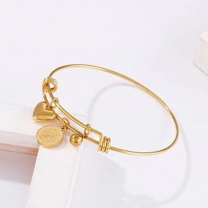 Gold stainless steel coin bracelet with Elizabeth II charm and heart pendant on white blocks
