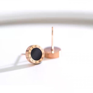 Elegant rose gold Roman numeral stud earrings with a black center on a white background