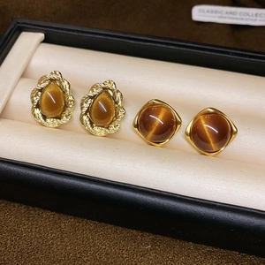 Detailed macro view of vintage gold tiger eye stone square and teardrop earrings