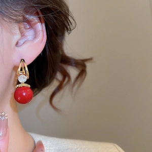 Gros plan d'un mannequin portant des boucles d'oreilles en zircon rouge et métal doré