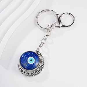 Detail of silver crescent moon keychain with blue evil eye and tree of life design