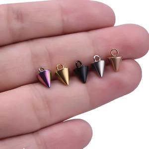 Detailed view of small conical stainless steel pendants in five colors on a person's finger