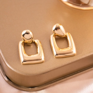 Detail view of gold-plated hollow geometric rectangle drop earrings with metallic luster