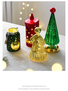 Close-up of festive LED glass Christmas tree, red reindeer candle, and golden angel decor