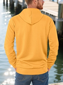 Detail of yellow hoodie featuring textured geometric jacquard fabric and relaxed fit