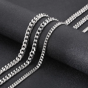 Detailed view of three silver stainless steel Cuban link chains on a black textured background