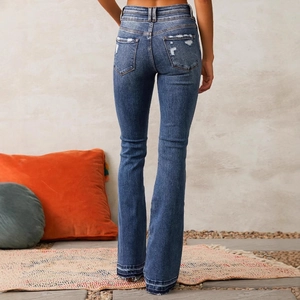 Vintage dark blue flare jeans with distressed back pockets and raw hems on model