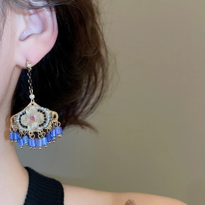 Détail de boucles d'oreilles éventail vintage avec fleurs roses et pampilles bleues
