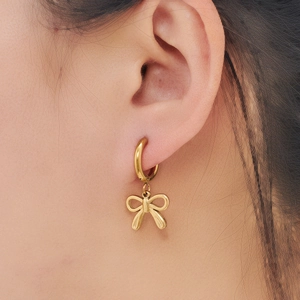 Polished gold bow pendant hoop earrings on model showing elegant stainless steel jewelry
