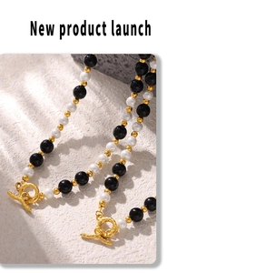 Detail of beaded necklace with black agate and white pearls featuring a golden OT clasp