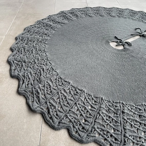 Detailed close-up of grey knitted Christmas tree skirt with hollow lace wavy edges and ties
