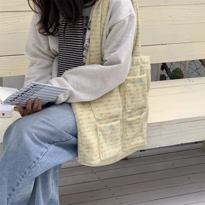 Detail of yellow tweed tote bag with four buttoned front pockets in a lifestyle setting