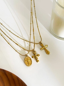 Detailed close-up of three vintage gold cross pendants with textured beaded and relief designs