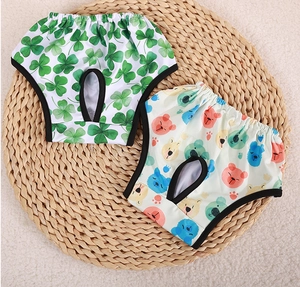 Detail view of dog diapers with green clover and colorful bear prints on a straw mat
