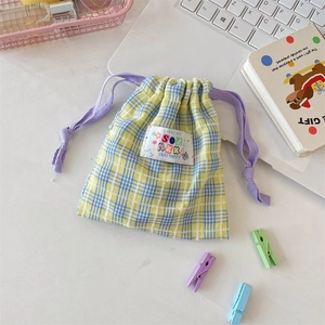 Détail du sac de rangement à carreaux jaune et bleu avec cordon violet et étiquette
