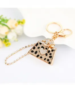 Detailed view of leopard print mini handbag keychain with sparkling rhinestones and gold bow