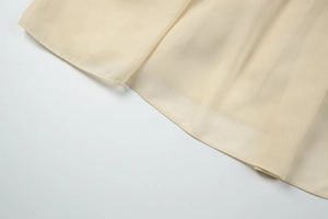 Detailed view of beige chiffon fabric layers with high-quality hem stitching