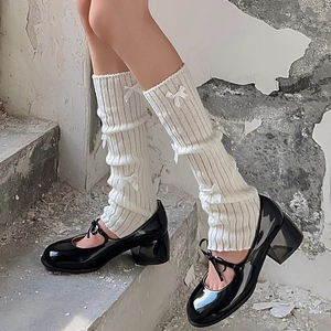Détail de jambières en tricot blanc avec nœuds et chaussures Mary Jane noires